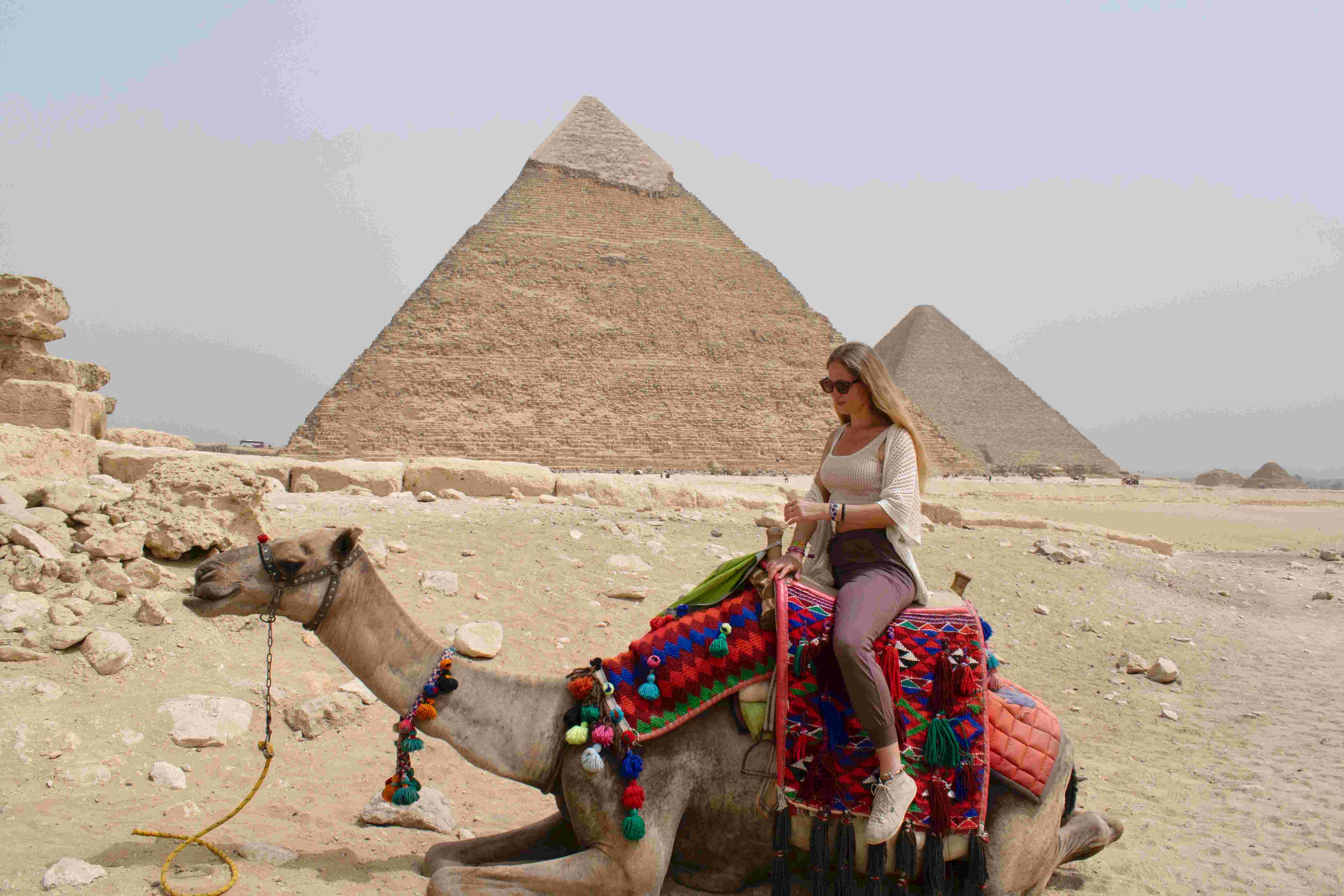 Tourists on a camel ride with pyramids in the background